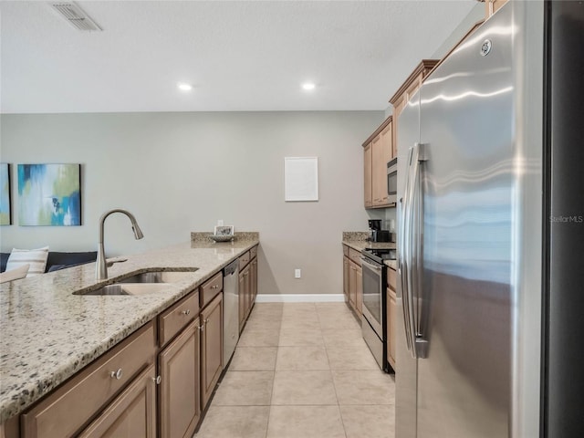 kitchen featuring light stone counters, sink, light tile patterned floors, and appliances with stainless steel finishes