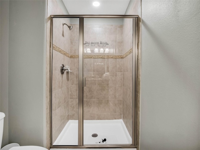 bathroom with toilet and a shower with shower door