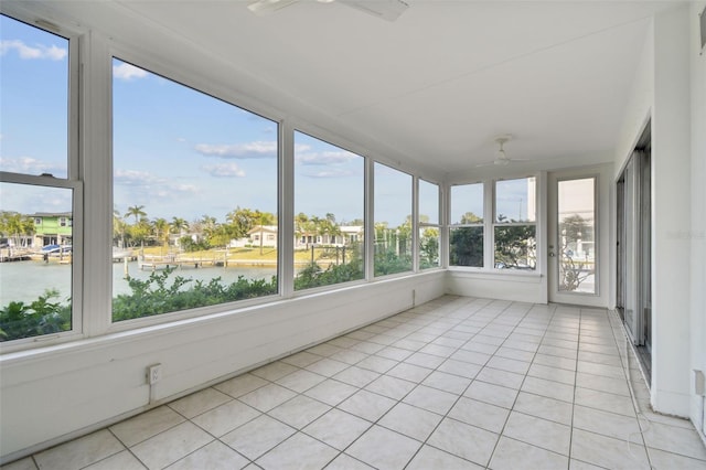 unfurnished sunroom with ceiling fan and a water view