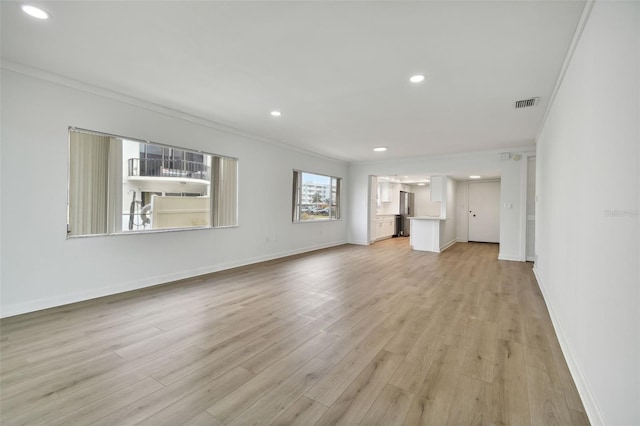 unfurnished living room featuring ornamental molding and light wood-type flooring