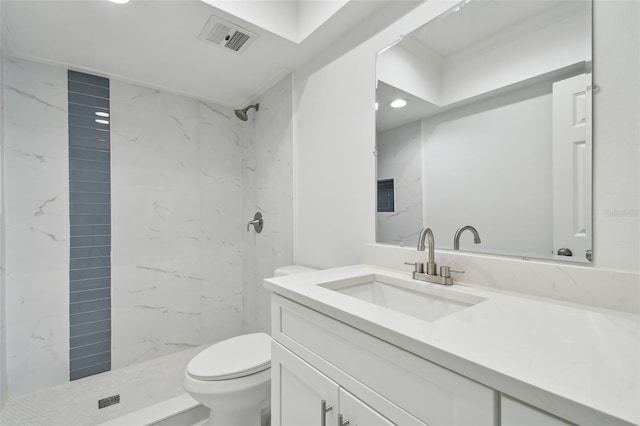 bathroom with tiled shower, vanity, and toilet