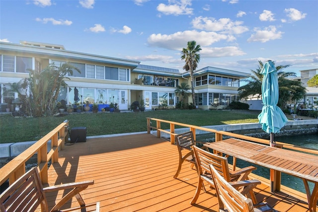 view of dock featuring a deck with water view and a yard