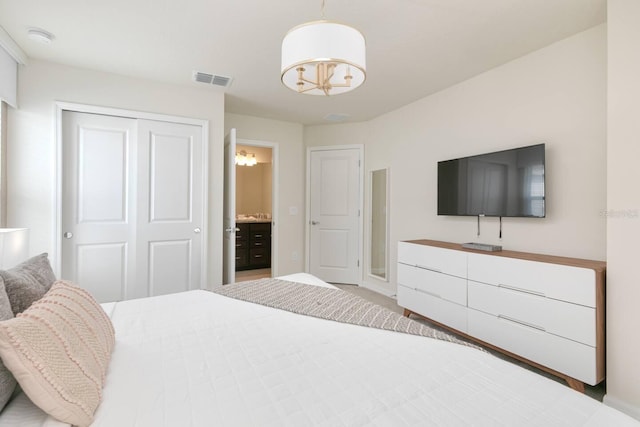 bedroom with ensuite bath, a closet, and an inviting chandelier