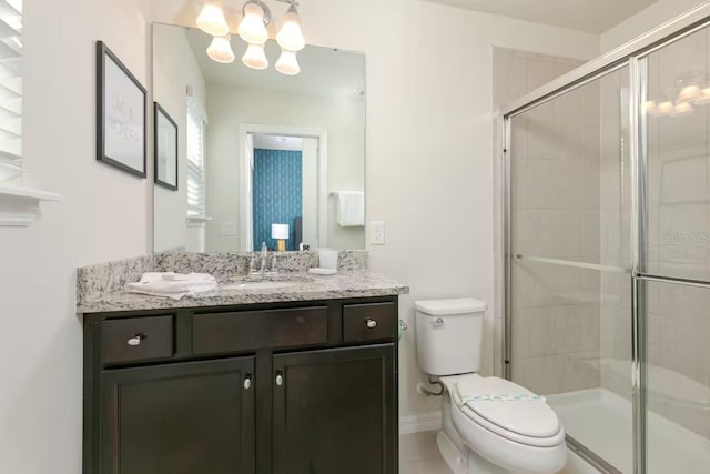 bathroom with vanity, an inviting chandelier, toilet, and a shower with shower door