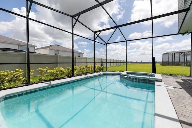 view of pool with a lawn, glass enclosure, a patio area, and an in ground hot tub