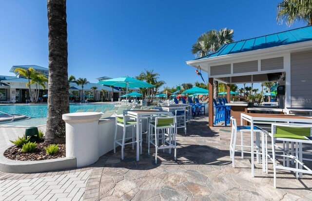 view of patio / terrace with exterior bar and a community pool