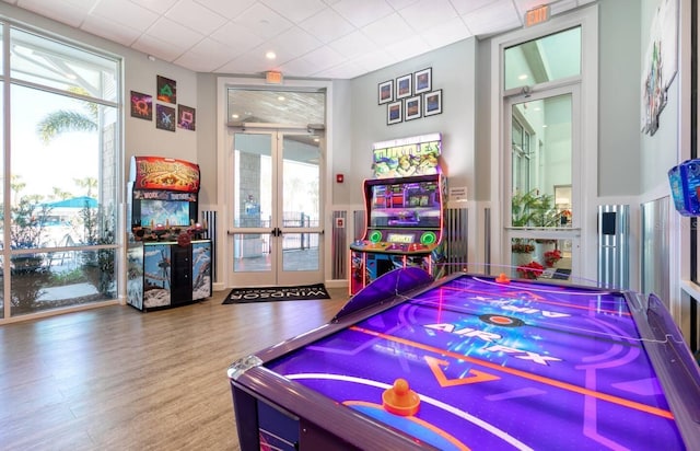 recreation room featuring french doors, a paneled ceiling, and wood-type flooring