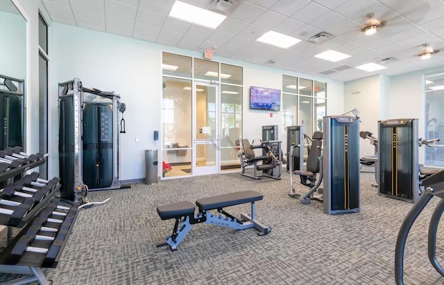 exercise room with a paneled ceiling and carpet