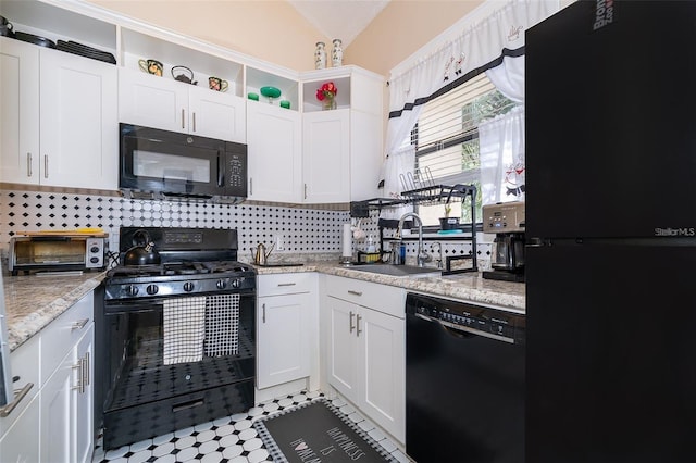 kitchen featuring lofted ceiling, sink, white cabinetry, light stone countertops, and black appliances