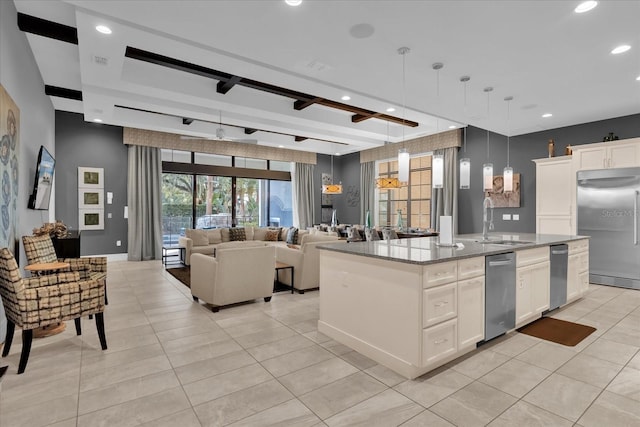 kitchen with hanging light fixtures, stainless steel appliances, white cabinetry, and a kitchen island with sink