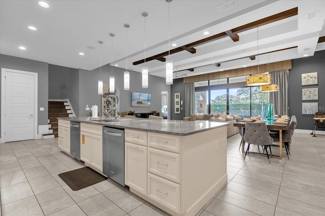 kitchen with light stone counters, beam ceiling, a center island with sink, white cabinetry, and hanging light fixtures