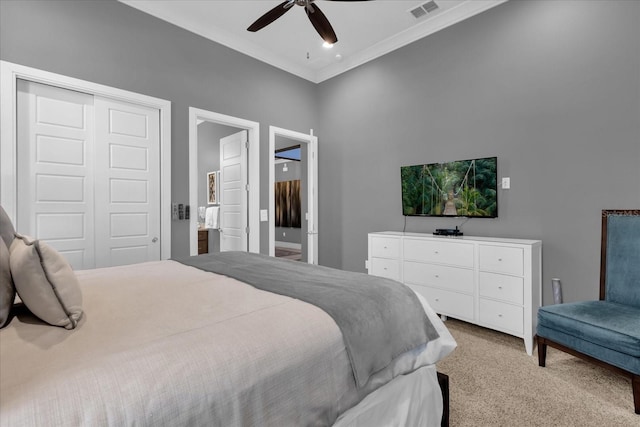 carpeted bedroom featuring ceiling fan, ensuite bath, ornamental molding, and a closet