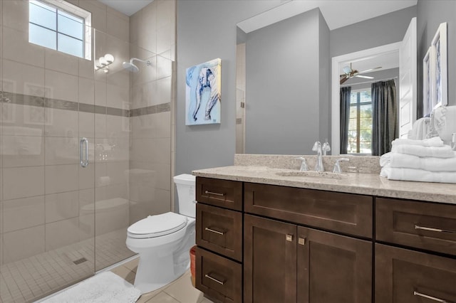 bathroom with tile patterned floors, vanity, a shower with door, ceiling fan, and toilet