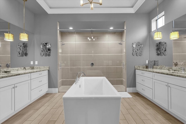 bathroom featuring a raised ceiling, vanity, shower with separate bathtub, and hardwood / wood-style flooring