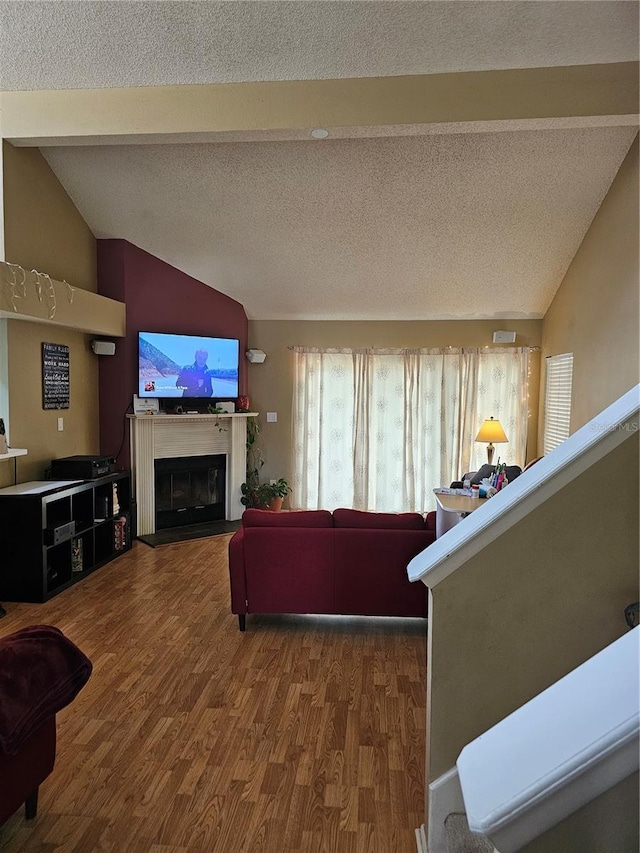 living room with vaulted ceiling with beams, hardwood / wood-style floors, and a textured ceiling