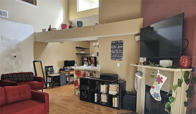 living room with light wood-type flooring and a towering ceiling