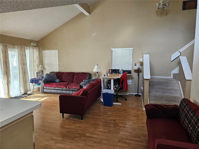 living room with vaulted ceiling with beams, wood-type flooring, and a textured ceiling