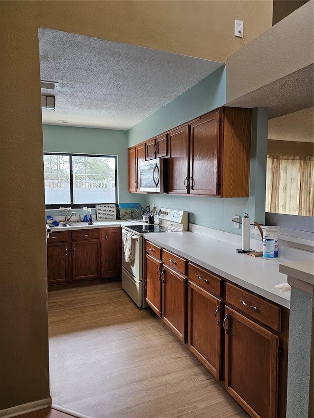 kitchen with sink, light hardwood / wood-style flooring, a textured ceiling, and appliances with stainless steel finishes