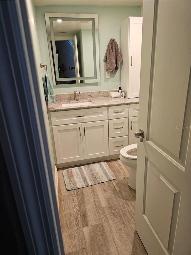 bathroom with toilet, vanity, and hardwood / wood-style flooring