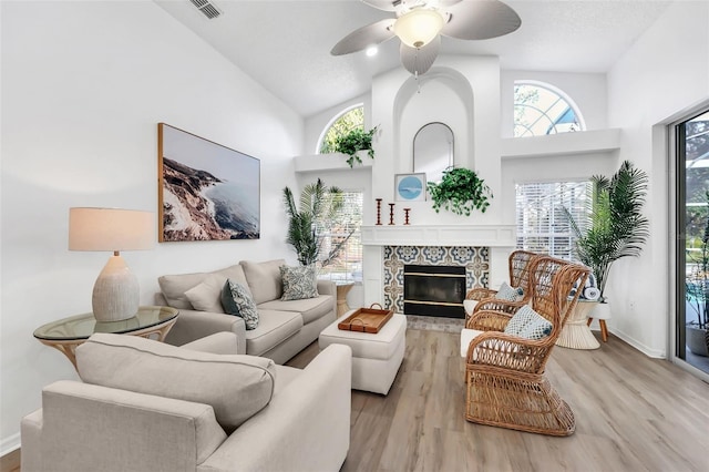 living room with ceiling fan, light hardwood / wood-style floors, a fireplace, and a wealth of natural light