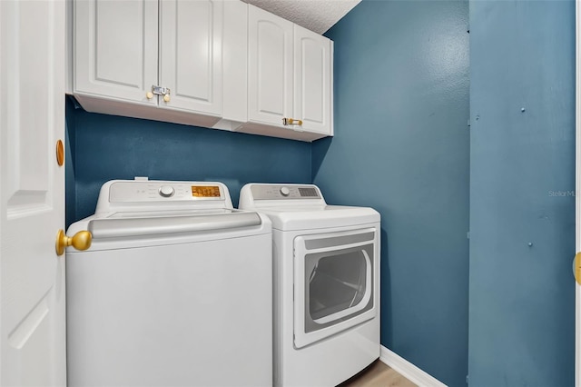 washroom featuring cabinets, a textured ceiling, and separate washer and dryer