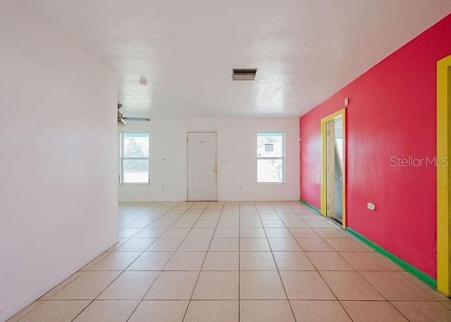 unfurnished room featuring a healthy amount of sunlight, light tile patterned floors, and ceiling fan