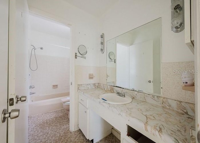 full bathroom featuring toilet, tiled shower / bath, tile walls, vanity, and tile patterned flooring