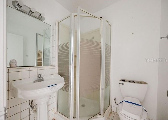 bathroom featuring tile walls, an enclosed shower, tasteful backsplash, tile patterned floors, and toilet