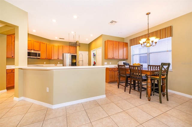 kitchen with hanging light fixtures, an inviting chandelier, a center island with sink, light tile patterned floors, and appliances with stainless steel finishes