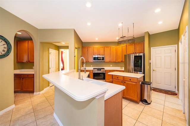 kitchen featuring light tile patterned flooring, sink, stainless steel appliances, and a kitchen island with sink