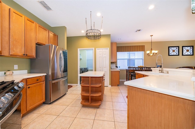 kitchen with black gas range, an inviting chandelier, a center island with sink, sink, and decorative light fixtures