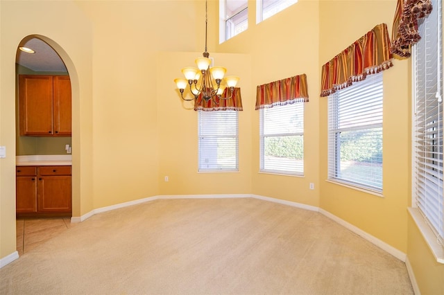 carpeted spare room with plenty of natural light and a notable chandelier