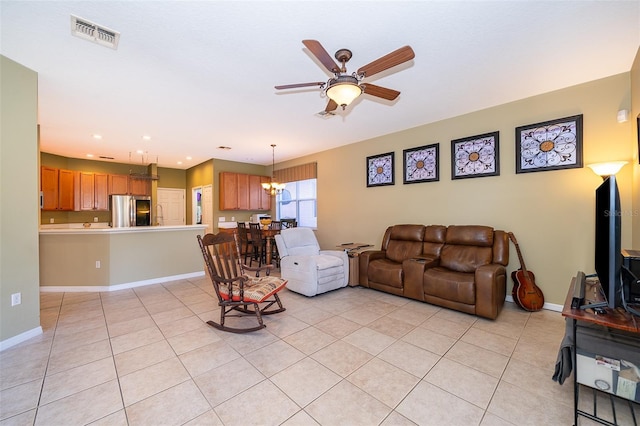 tiled living room with ceiling fan with notable chandelier