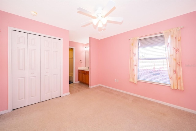 unfurnished bedroom with ceiling fan, light colored carpet, ensuite bath, and a closet