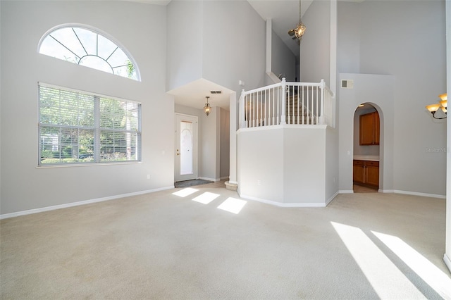 11313 Via Andiamo, Windermere, FL 34786 - unfurnished living room featuring a high ceiling, light carpet, arched walkways, and stairs
