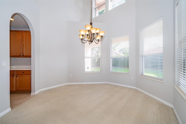 11313 Via Andiamo, Windermere, FL 34786 - unfurnished dining area with light carpet, plenty of natural light, a chandelier, a high ceiling, and arched walkways
