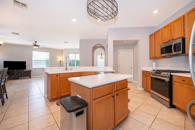 11313 Via Andiamo, Windermere, FL 34786 - kitchen featuring appliances with stainless steel finishes, a kitchen island, light countertops, light tile patterned floors, and ceiling fan