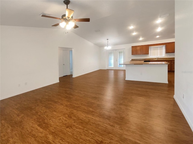 unfurnished living room with ceiling fan with notable chandelier, dark wood-type flooring, and lofted ceiling