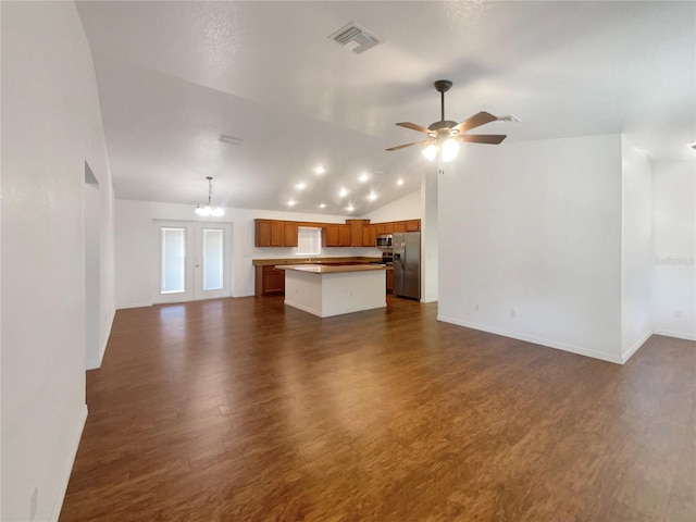 unfurnished living room with ceiling fan with notable chandelier, dark wood-type flooring, and lofted ceiling