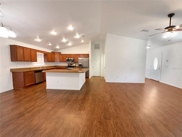 kitchen featuring dark hardwood / wood-style floors, a kitchen island, stainless steel appliances, and vaulted ceiling