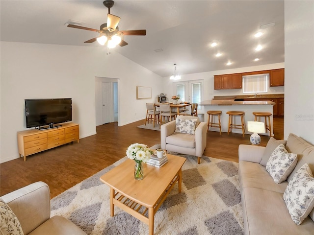 living room featuring ceiling fan with notable chandelier, wood-type flooring, and lofted ceiling