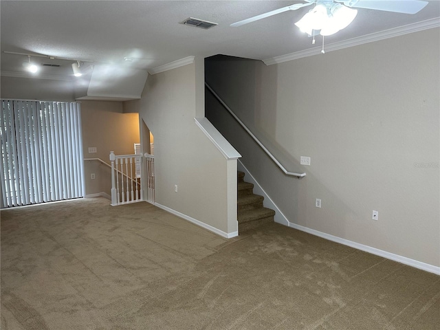 basement featuring carpet, a textured ceiling, rail lighting, and ornamental molding