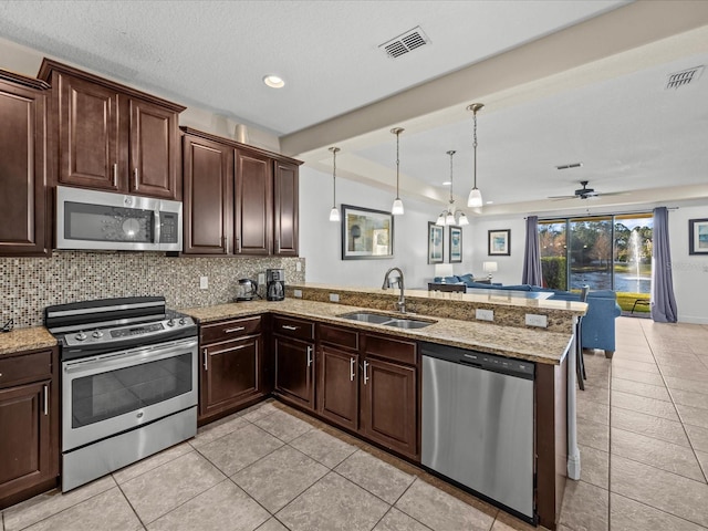 kitchen with sink, tasteful backsplash, decorative light fixtures, kitchen peninsula, and stainless steel appliances