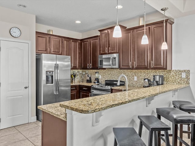 kitchen featuring a kitchen breakfast bar, decorative backsplash, decorative light fixtures, kitchen peninsula, and stainless steel appliances