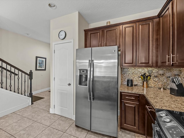 kitchen with tasteful backsplash, light stone counters, dark brown cabinets, light tile patterned floors, and appliances with stainless steel finishes