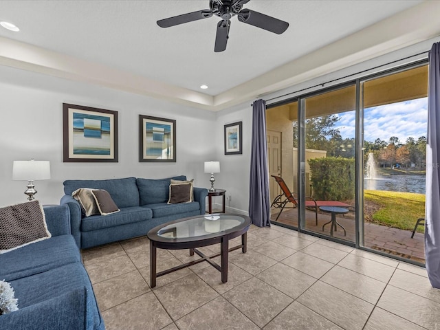 tiled living room with ceiling fan and a water view