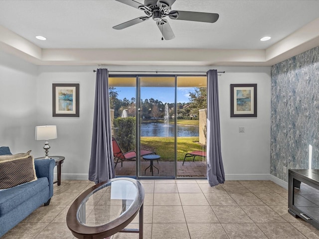 tiled living room with ceiling fan and a water view