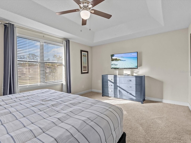 carpeted bedroom with a tray ceiling and ceiling fan