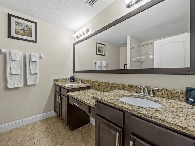 bathroom with vanity, a textured ceiling, tile patterned floors, and walk in shower