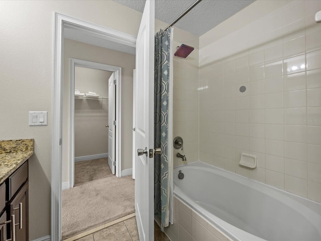 bathroom with tile patterned flooring, shower / bath combination with curtain, a textured ceiling, and vanity